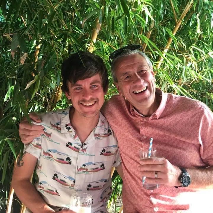 Chris and his dad laughing together in a garden